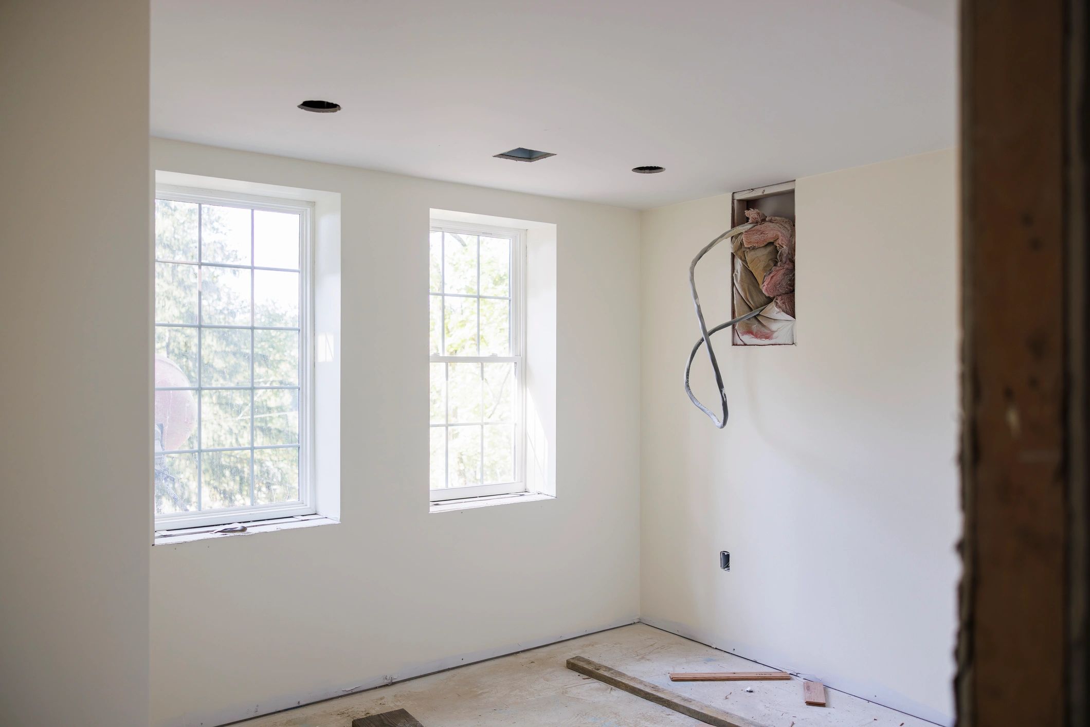 Newly renovated but unfinished room with bright windows in residential property. Interior remodeling project in progress.